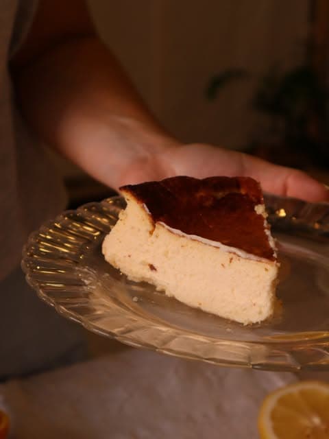 Fatia de tarte basca numa travessa de vidro, servida à mão